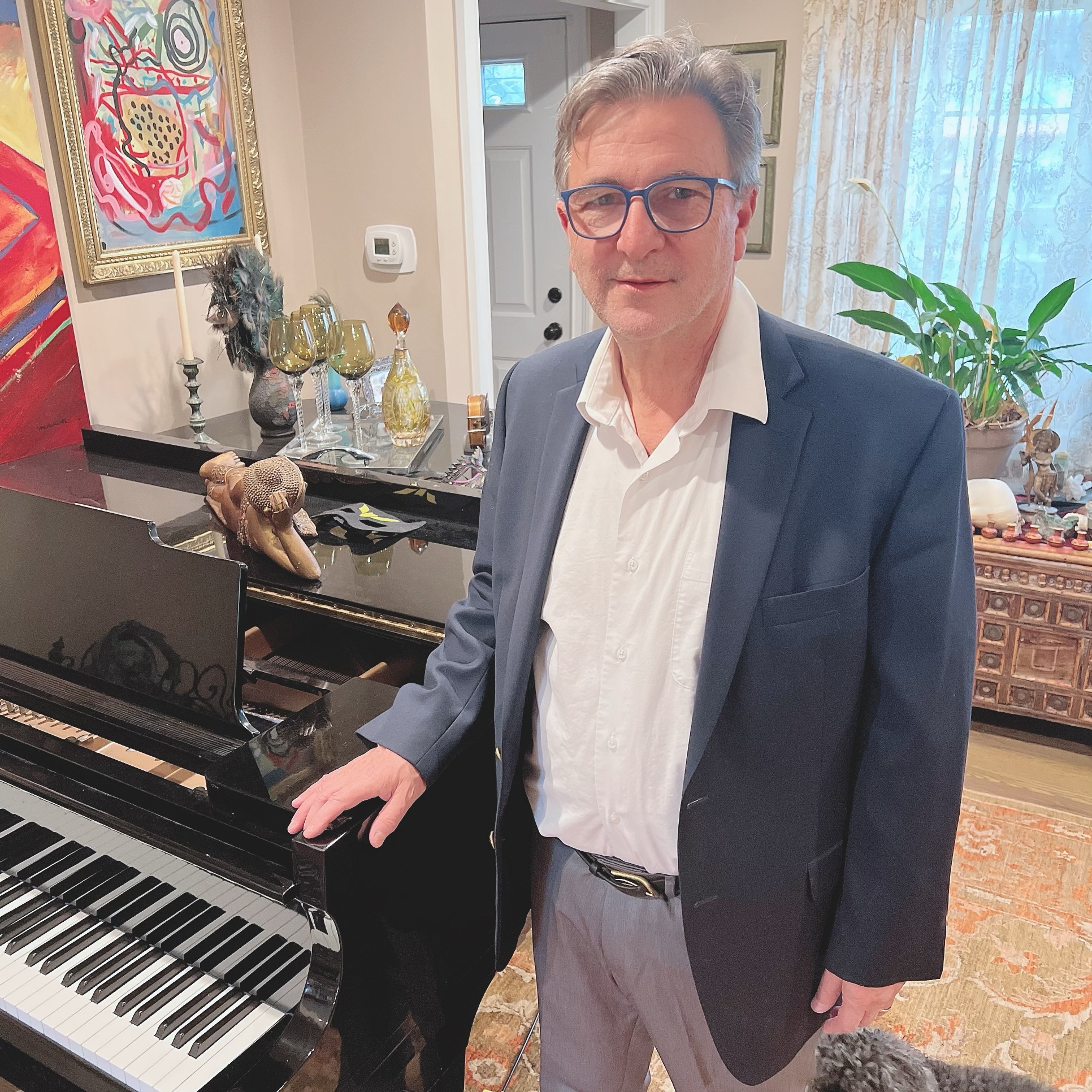 A man in a suit stands beside a piano, exuding a professional and elegant demeanor.